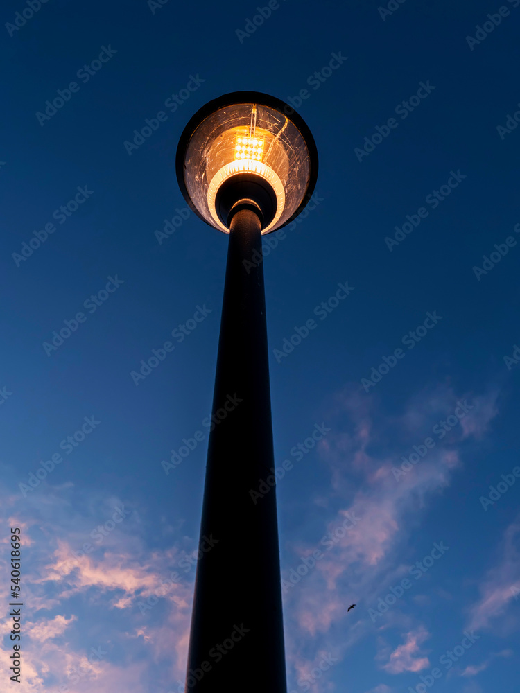 Modern powerful LED light in old style lantern against blue cloudy sunset sky. City and town illumination tool. Energy saving light.