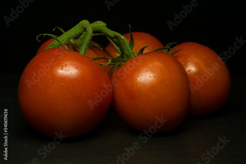 Red tomatoes on black background. Dark mood style.