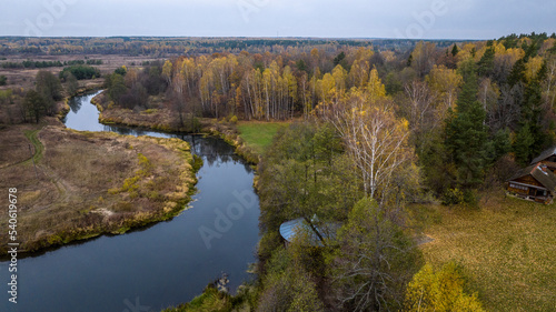 Fototapeta Naklejka Na Ścianę i Meble -  panoramic view from a drone on the edge of the forest with wooden houses and a river against the backdrop of autumn nature