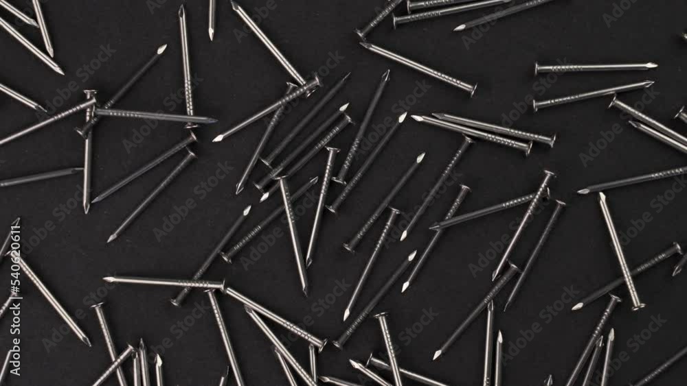 Top view of steel industrial nails on a black background. Carpentry tool close-up. Rotation Top view of steel industrial nails on a black background. Carpentry tool close-up. Rotation