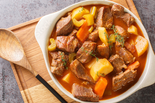 Traditional Irish stew of meat and vegetables in a thick sauce based on dark beer close-up in a pot on the table. Horizontal top view from above