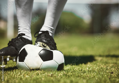 Soccer player feet, deflated soccer ball and sports, competition game and training on grass field, pitch and lawn. Closeup footballer boots puncture, broken and decrease air problem of flat equipment photo