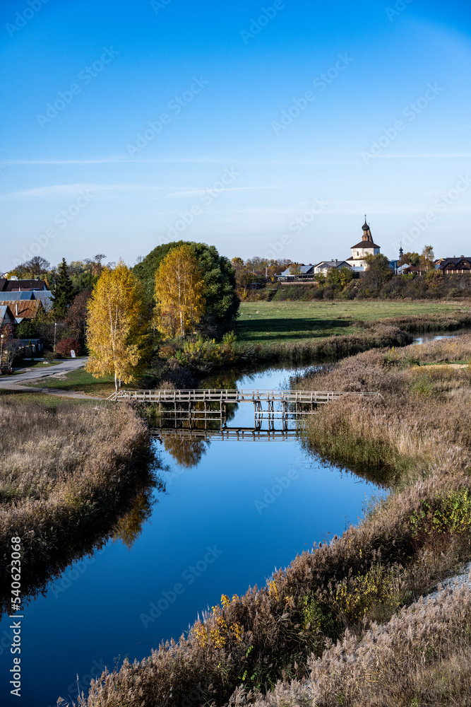 an old church against the backdrop of a river and an autumn sunny landscape