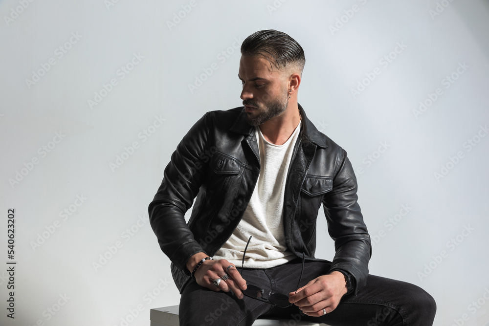 stylish man with modern hairstyle holding sunglasses and looking down side stylish man with modern hairstyle holding sunglasses and looking down side