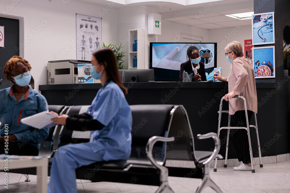 Elderly caucasian woman using walker signing at medical clinic. African american female receptionist attending a patient. Asian health professional explaining care to sick afro girl. Elderly caucasian woman using walker signing at medical clinic. African american female receptionist attending a patient. Asian health professional explaining care to sick afro girl.