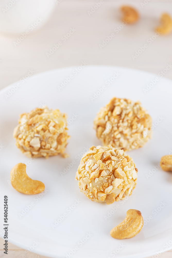 Candy truffles brigadeiro with cashew nuts on a white plate on the table. Candy truffles brigadeiro with cashew nuts on a white plate on the table.