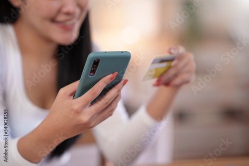 Close-up of woman enjoying the peace of mind of online shopping on mobile using credit card at home.