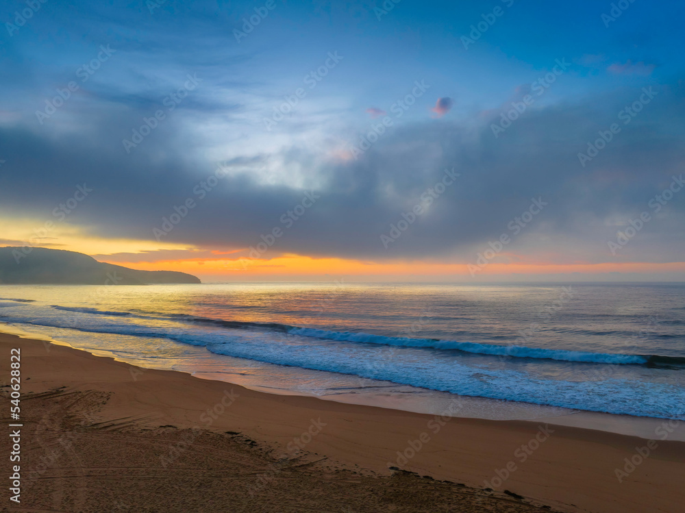 Peaceful sunrise over the ocean with small waves and clouds