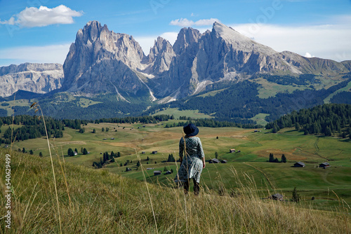 Young traveller woman enoys the view into the spectacular dolomite mountains: disctinctive sassolungo group. travel and adventure concept. photo