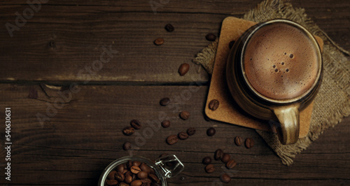 Ceramic cup with coffee and coffee beans on a dark background