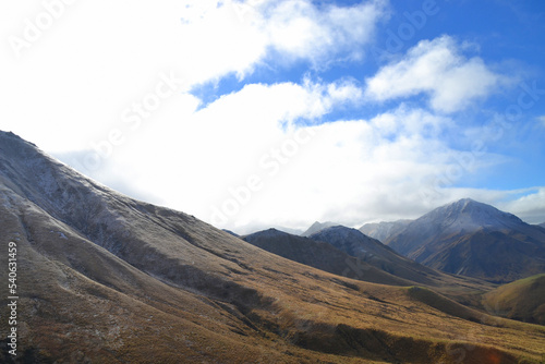 View of snow-topped, tussock-covered mountains in a rugged Danseys Pass, Maniototo District, New Zealand