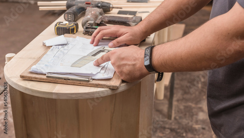 Bilde på lerret A contractor points to the perspective drawing of a custom solihiya shoe bench to be built at a furniture workshop