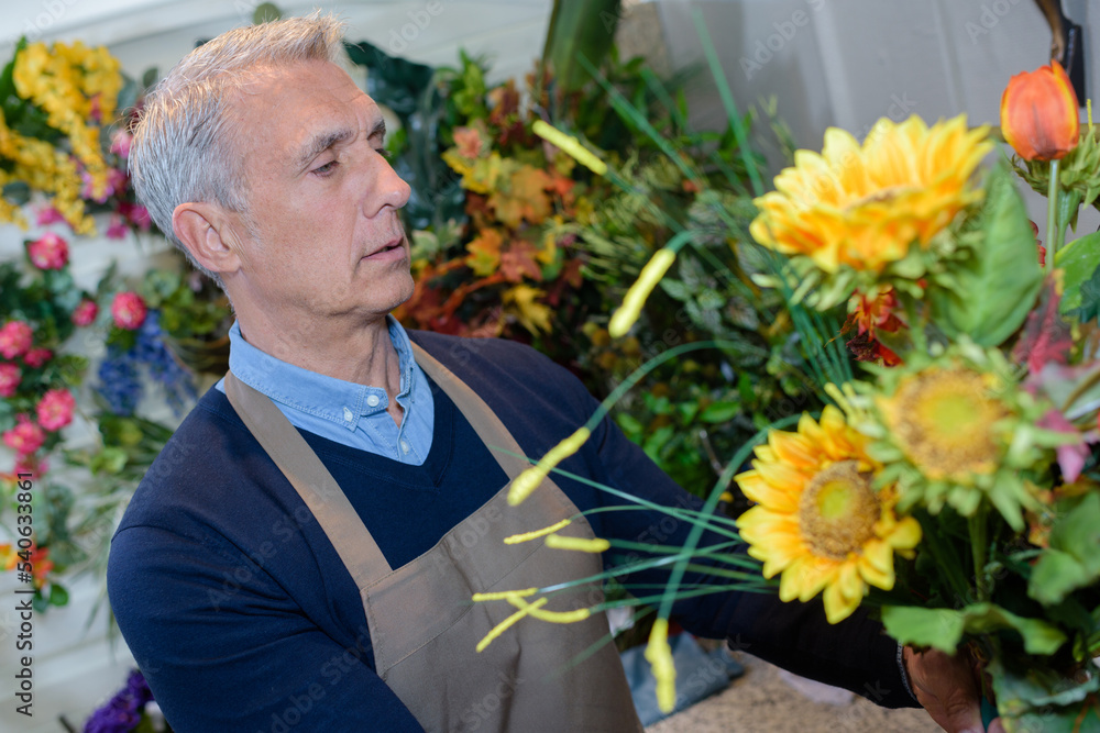 senior male florist working at flower shop senior male florist working at flower shop