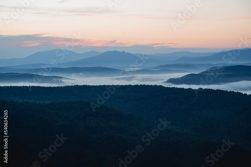 Morning in the mountains fog rises over the valley of the mountains, the first hour of dawn, a cold morning, smoke spreads below the river. © Aleksey