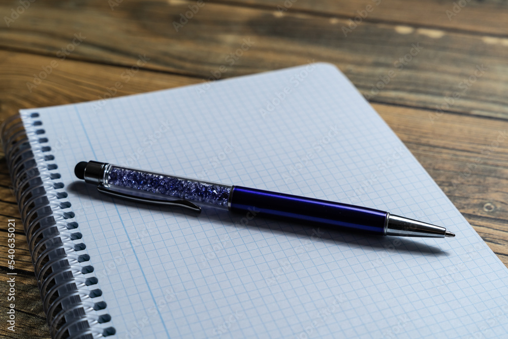 Empty notebook sheet with a pen on wooden background and copy space. Empty notebook sheet with a pen on wooden background and copy space.