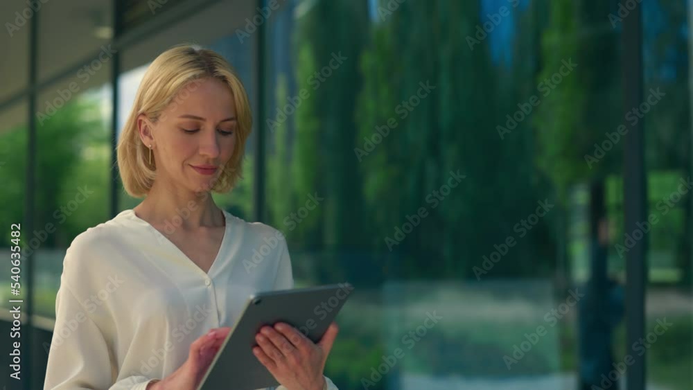 Side view of the business woman in formal suit going, using the tablet for working purposes. Female worker texting, swiping apps using digital tablet. People and technology concept. Side view of the business woman in formal suit going, using the tablet for working purposes. Female worker texting, swiping apps using digital tablet. People and technology concept.
