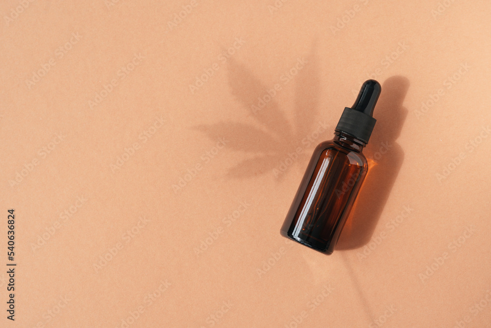 Amber glass dropper bottles with cannabis oil used for medical purposes on beige background. Daylight and the shadow of a hemp leaf. Soothing cbd oil. Alternative Medicine. Copy space Amber glass dropper bottles with cannabis oil used for medical purposes on beige background. Daylight and the shadow of a hemp leaf. Soothing cbd oil. Alternative Medicine. Copy space