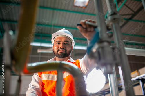 professional technician engineer with safety hard hat working to maintenance construction equipment in industrial factory, worker is checking or repair the machine.