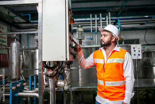 Asian engineer worker wearing safety uniform control operating machine and turn on switch in industry factory.