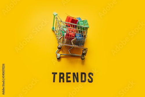 Ecommerce Retail Shopping trends concept. Word Trends and mini shopping cart with box on yellow background.