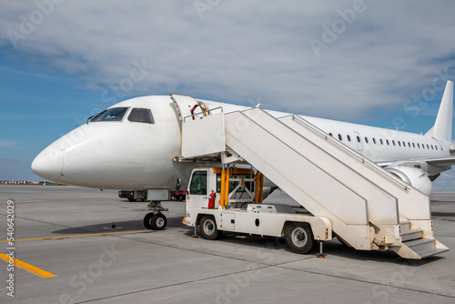 White passenger airliner with a boarding steps on the airport apron