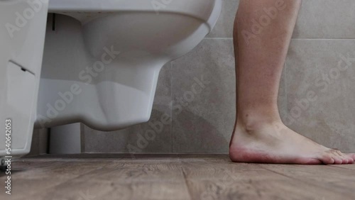 A man goes to the toilet in the toilet, takes off his denim shorts and begins the process of defecation. Healthy digestive tract and intestines