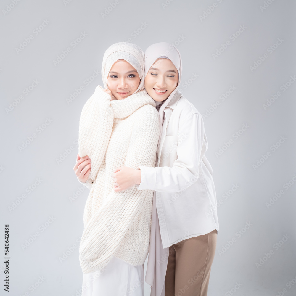 Portrait of two beautiful Muslim young women wearing modern and stylish casual wear with hijab isolated from studio background. Modern hijab fashion and beauty concept Portrait of two beautiful Muslim young women wearing modern and stylish casual wear with hijab isolated from studio background. Modern hijab fashion and beauty concept