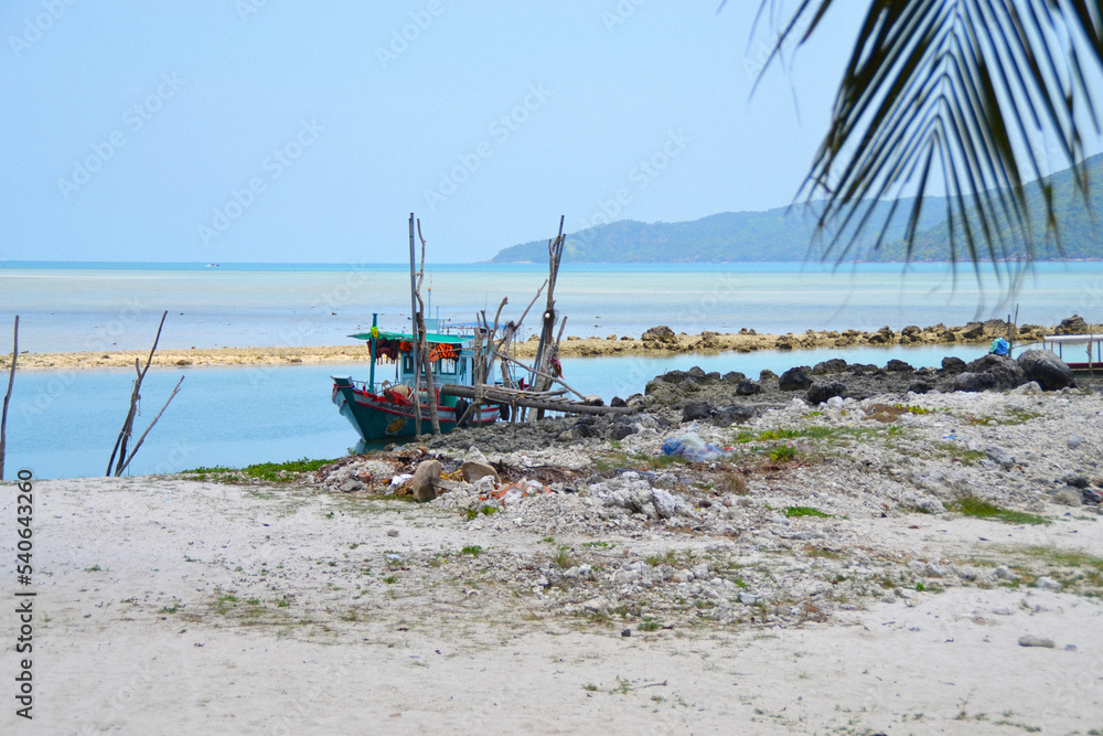 Fishing boat moored at the beach with a blue sky and ocean background, in Koh Samui, Thailand