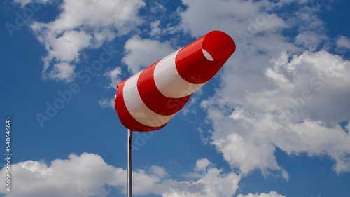 Windsock. Windsock flag. Wind direction indicator. Wind intensity. Windsock in front of blue sky.