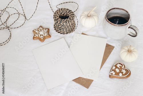 Christmas stationery. Closeup of empty greeting card, invitation mockup. Cup of coffee, white pumkins and decorative rope. Linen tablecloth. Gingerbread cookies. Winter, Thanksgiving flatlay, top view