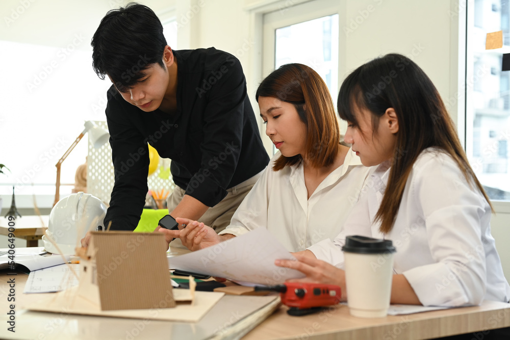 Group of young people working together of architectural project, collaborating with team leader at creative office Group of young people working together of architectural project, collaborating with team leader at creative office