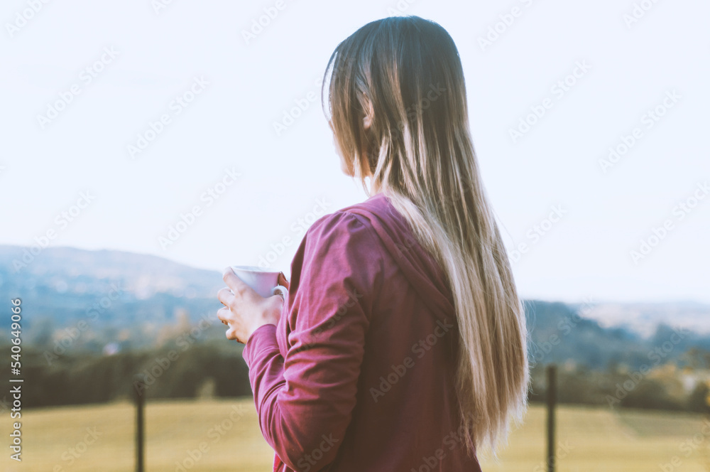 young woman with a cup of coffee in the background of the mountains young woman with a cup of coffee in the background of the mountains