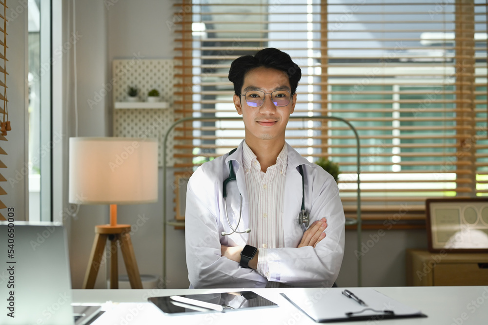 Confident doctor in white uniform sitting with arms crossed and smiling to camera Confident doctor in white uniform sitting with arms crossed and smiling to camera