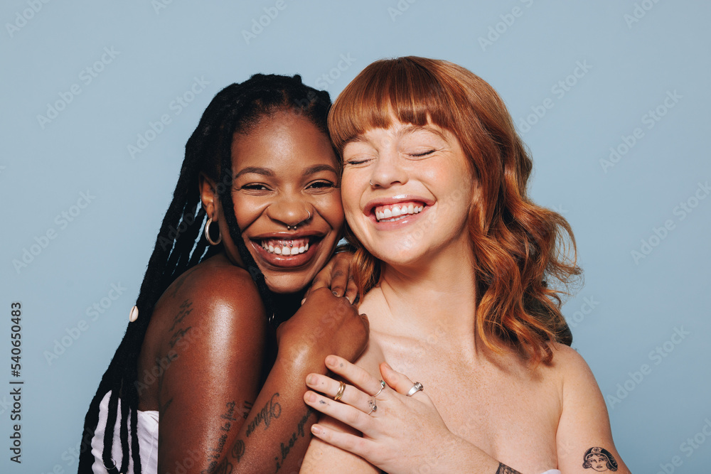 Cheerful young women with different skin tones smiling while standing together Cheerful young women with different skin tones smiling while standing together