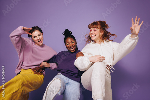 Energetic female friends dancing and celebrating in a studio photo