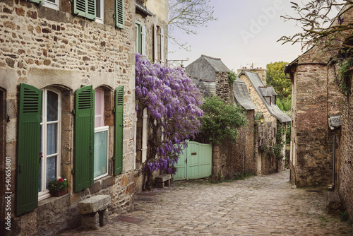 Fototapeta Naklejka Na Ścianę i Meble -  Picturesque street of the medieval town of Dinan in spring in France, Brittany. Blooming wisteria on a medieval street. The fabulous city of Dinant, a popular tourist destination in France