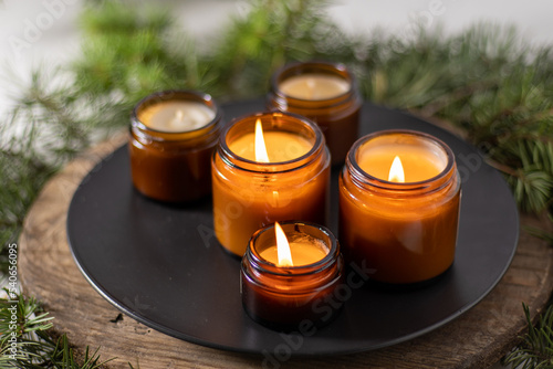 Soy candles burn in glass jars. Comfort at home. Candle in a brown jar. Scent and light. Scented handmade candle. Aroma therapy. Christmas tree and winter mood. Cozy decor. Festive decoration