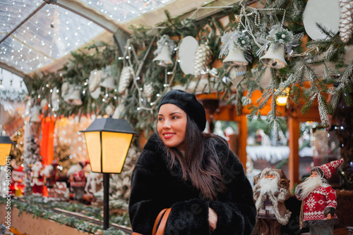 Beautiful dark-haired young woman in an eco fur coat walks around the city and does Christmas shopping. New Year holidays. Present. Holidays. Winter.