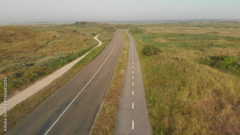 The camera flyes forward following the empty road in a rural area during the foggy and sunny dusk The camera flyes forward following the empty road in a rural area during the foggy and sunny dusk