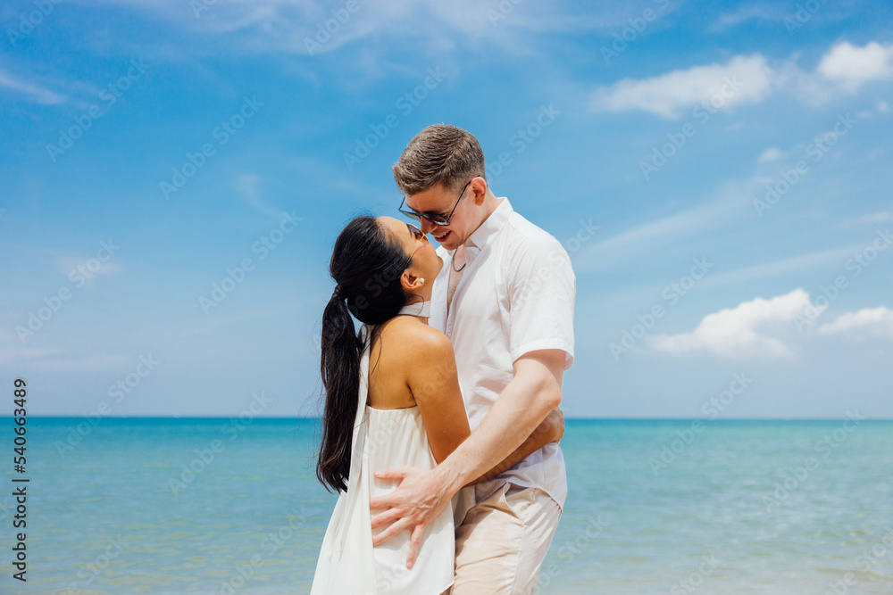 Man and woman couple hugging each other kissing at seaside,Loving young couple standing in each other's arms and kissing on a sandy beach at dusk