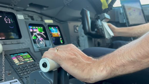 Close view a jet engine throttles and control column operated by first officer during a descent. Instruments unfocused. 4K photo