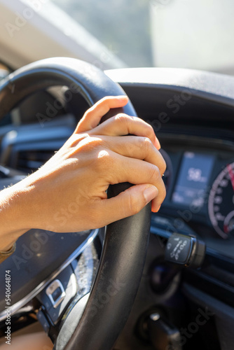 La main d'une femme sur un volant en cuir noir d'une voiture moderne