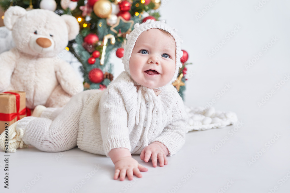 Santa baby. Christmas tree background. Happy New Year! Child in knitted suit Santa baby. Christmas tree background. Happy New Year! Child in knitted suit