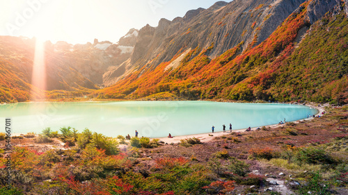 Panoramic view over Esmeralda lagoon and magical austral forest, and high mountains in Tierra del Fuego National Park, Patagonia, Argentina, golden Autumn with lens flare direct sunlight