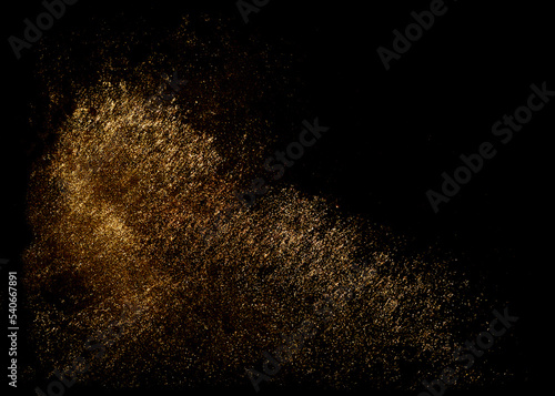 Golden sequins glisten with dust isolated on a black background. Horizontal abstract background with sparkling dust, space for text
