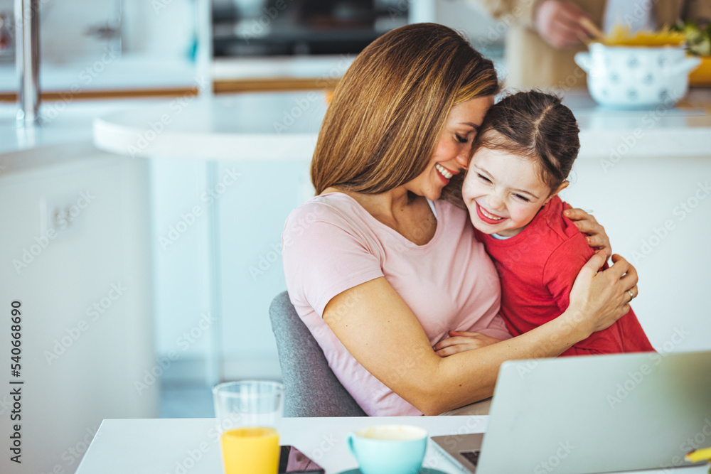 Mother and daughter using laptop and Internet. Freelancer workplace in cozy kitchen. Woman and child girl together. Concept of female business, working mom, freelance, home office. Lifestyle moment. Mother and daughter using laptop and Internet. Freelancer workplace in cozy kitchen. Woman and child girl together. Concept of female business, working mom, freelance, home office. Lifestyle moment.