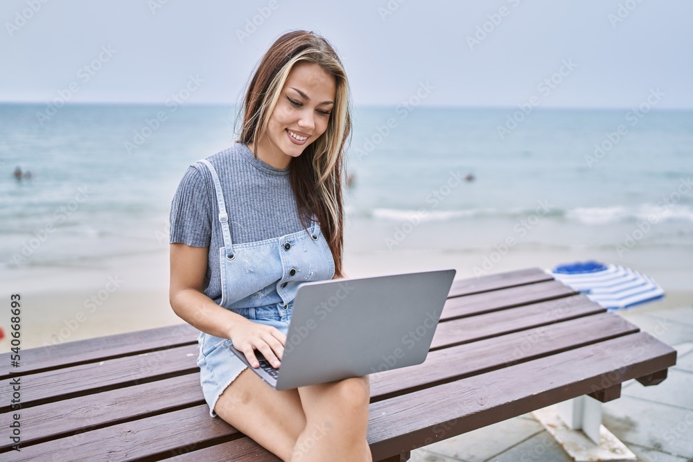 Young caucasian woman working using computer laptop outdoors looking positive and happy standing and smiling with a confident smile showing teeth