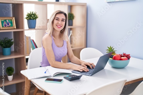 Young woman sitting on table teleworking at home