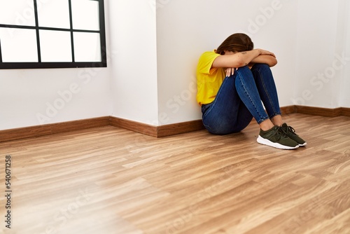 Young woman sitting on floor crying at empty room