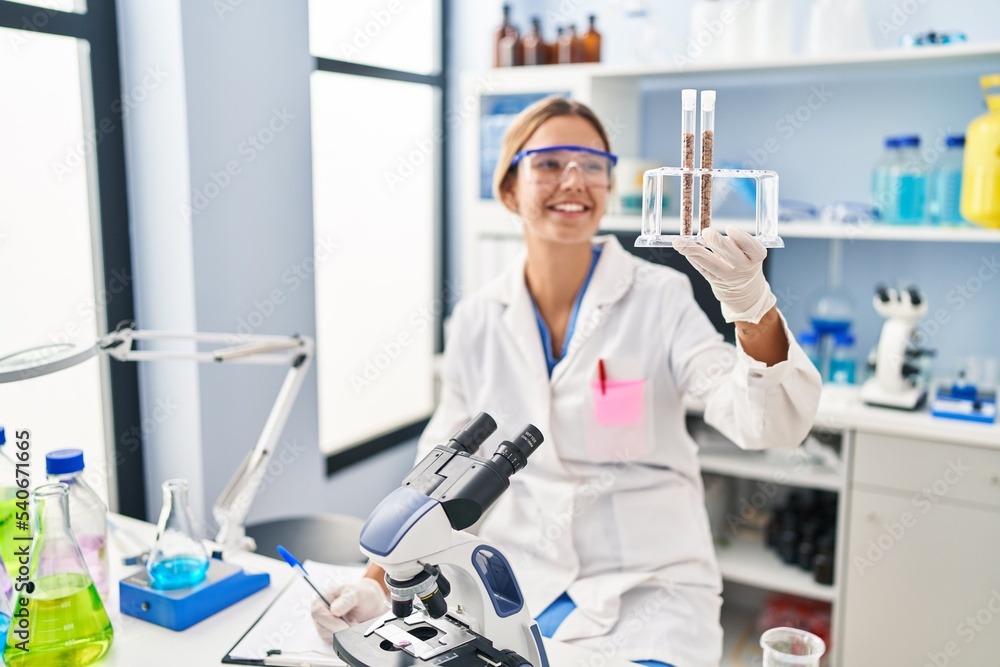 Young hispanic woman scientist write on document holding test tubes at laboratory Young hispanic woman scientist write on document holding test tubes at laboratory